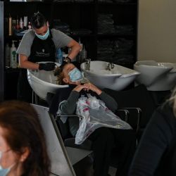 Los peluqueros que usan una máscara facial mientras ella se corta el pelo a los clientes, también usan una máscara facial en el sur de Atenas el 4 de mayo de 2020, el primer día del encierro en Grecia, después de un largo período de encierro debido a la pandemia de Covid-19 causado por el nuevo coronavirus. / AFP / ARIS MESSINIS | Foto:AFP