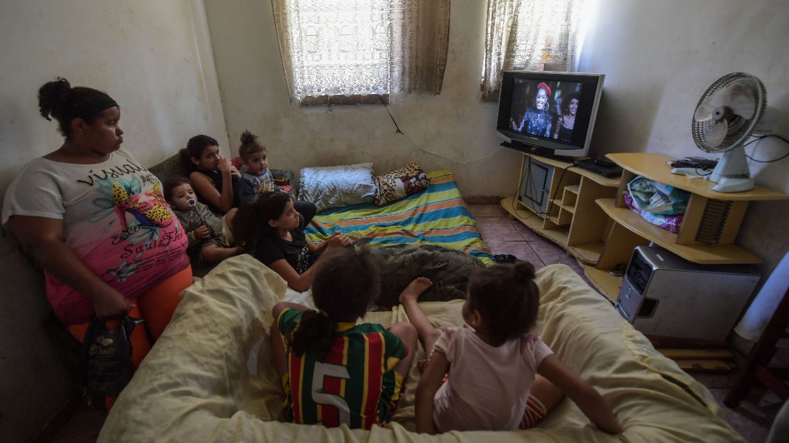 Viviane Rodrigues Vieira de Lima (L) and her daughters watch TV at home, in the Paraisopolis favela in Sao Paulo, Brazil, during the COVID-19 coronavirus pandemic on April 23, 2020.