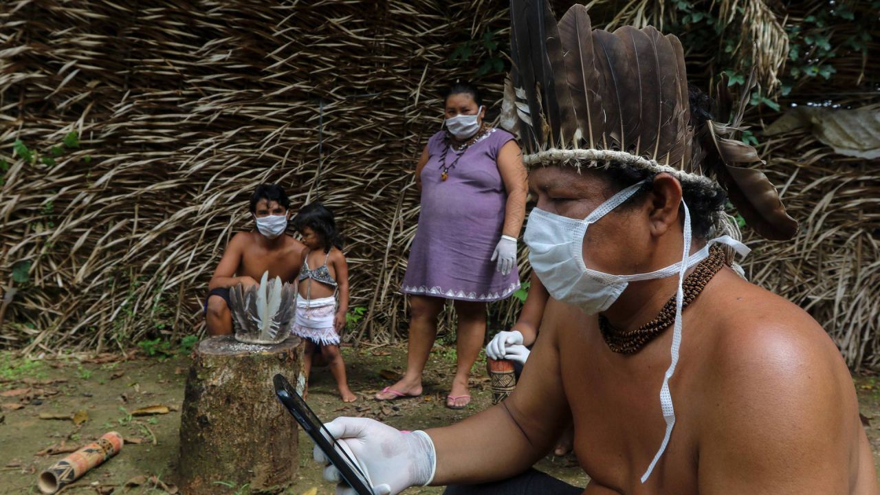 Se ve a los indígenas Satere-mawe usando un teléfono inteligente para contactar a un médico en el estado de Sao Paulo para recibir orientación médica en medio de la nueva pandemia de coronavirus COVID-19 en la comunidad Sahu-Ape, a 80 km de Manaus, estado de Amazonas, Brasil, el 5 de mayo. , 2020. - El estado brasileño de Amazonas, hogar de la mayoría de los pueblos indígenas del país, es una de las regiones más afectadas por la pandemia, con más de 500 muertes hasta la fecha según el ministerio de salud. (Foto por RICARDO OLIVEIRA / AFP) | Foto:AFP