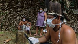 Se ve a los indígenas Satere-mawe usando un teléfono inteligente para contactar a un médico en el estado de Sao Paulo para recibir orientación médica en medio de la nueva pandemia de coronavirus COVID-19 en la comunidad Sahu-Ape, a 80 km de Manaus, estado de Amazonas, Brasil, el 5 de mayo. , 2020. - El estado brasileño de Amazonas, hogar de la mayoría de los pueblos indígenas del país, es una de las regiones más afectadas por la pandemia, con más de 500 muertes hasta la fecha según el ministerio de salud. (Foto por RICARDO OLIVEIRA / AFP)