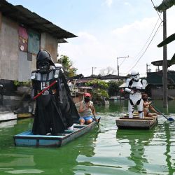 Representantes juveniles locales vistieron a Stormtroopers y Darth Vader (L-in black) de la franquicia de películas de Star Wars en botes de madera alrededor de una aldea sumergida para recordarles a los residentes que se queden en casa durante la cuarentena comunitaria mejorada en los suburbios de Manila el 6 de mayo de 2020, como parte de los esfuerzos del gobierno para combatir la propagación del coronavirus COVID-19. (Foto por Ted ALJIBE / AFP) | Foto:AFP