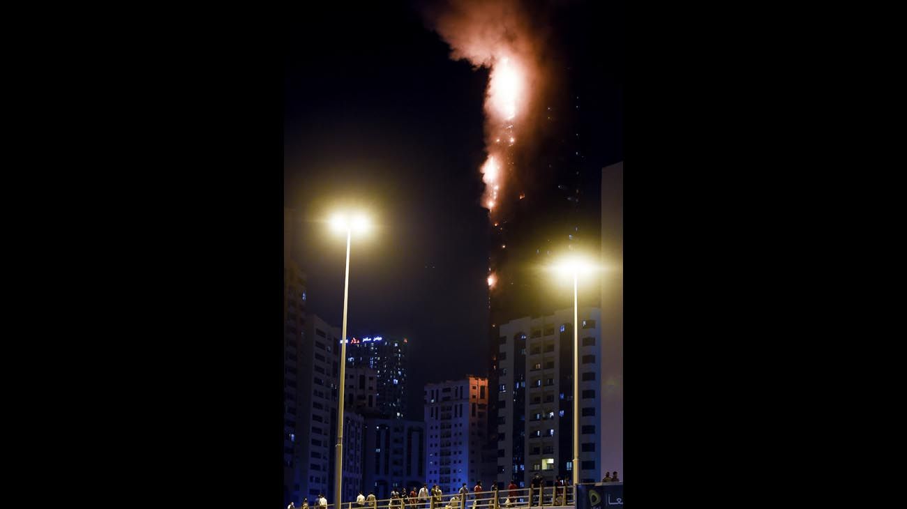  La gente se para en un puente y observa un incendio que se produce en una torre de 48 pisos en Sharjah, en los Emiratos Árabes.