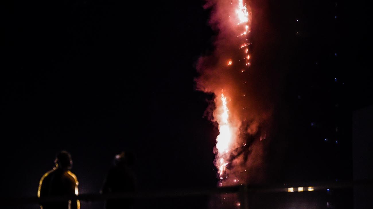  La gente se para en un puente y observa un incendio que se produce en una torre de 48 pisos en Sharjah, en los Emiratos Árabes.