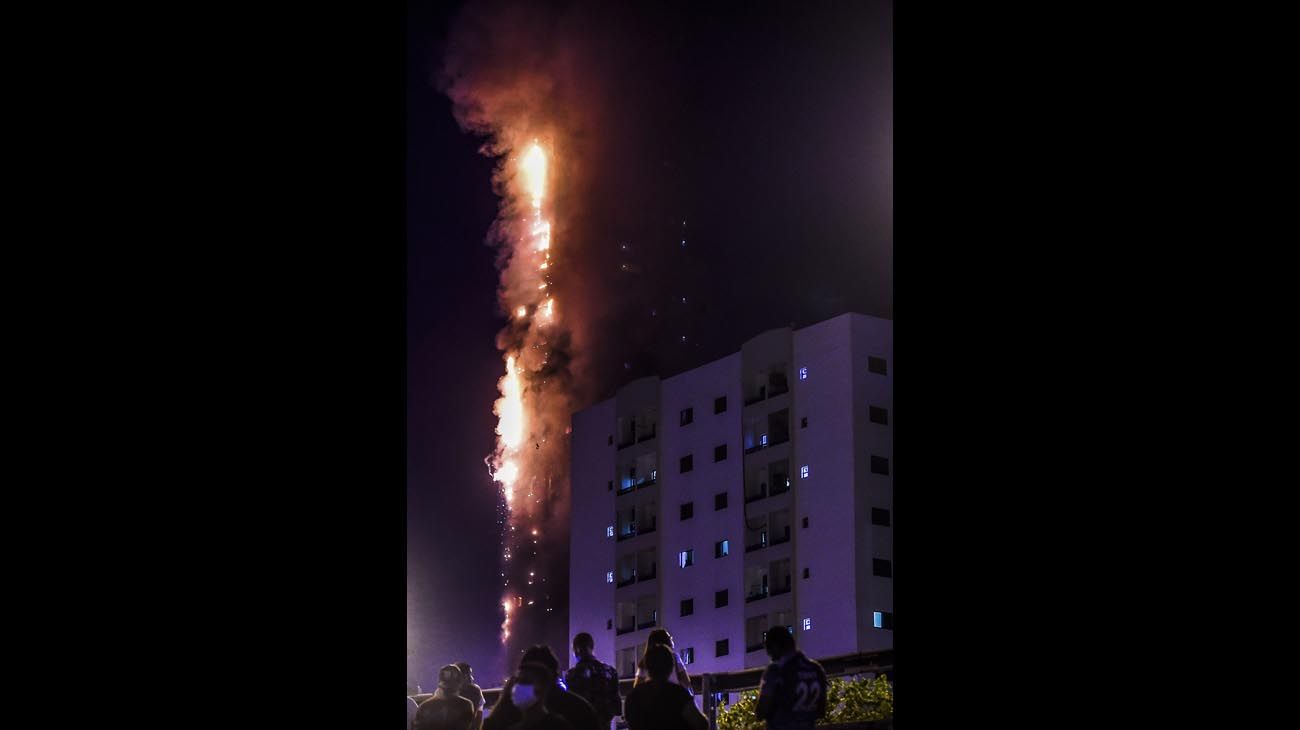  La gente se para en un puente y observa un incendio que se produce en una torre de 48 pisos en Sharjah, en los Emiratos Árabes.