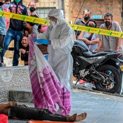 Un oficial de policía con un traje protector descubre el cadáver de un hombre que murió en la calle en Medellín, Colombia, el 6 de mayo de 2020 en medio de la pandemia de coronavirus Covid-19. - Más de 15,000 personas han sido asesinadas por el nuevo coronavirus en América Latina y el Caribe a partir de las 0230 GMT del miércoles, según un recuento de AFP basado en informes oficiales. (Foto de JOAQUIN SARMIENTO / AFP) | Foto:AFP