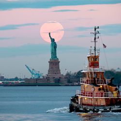La luna llena de mayo, conocida como la luna llena de flores y es la última superluna del año, se encuentra detrás de la Estatua de la Libertad el 7 de mayo de 2020 en la ciudad de Nueva York. (Foto de Johannes EISELE / AFP) | Foto:AFP