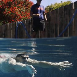 El nadador olímpico Michael Andrew es entrenado por su padre Peter mientras se entrena en una piscina residencial el 6 de mayo de 2020 en San Diego, California. Debido a la pandemia de COVID-19, muchos atletas de élite se han visto obligados a ajustar las ubicaciones y los regímenes de entrenamiento. Sean M. Haffey / Getty Images / AFP | Foto:AFP