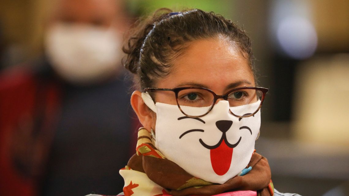A woman wearing a face mask decorated with an animal face waits in line for a rapid coronavirus test at a train station in Buenos Aires, Argentina, Friday, April 24, 2020.