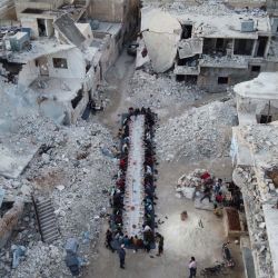 Los sirios desplazados se sientan en medio de las ruinas de su vecindario destruido mientras rompen el ayuno durante una comida Iftar organizada por una organización benéfica local en la ciudad de Atareb en el campo occidental controlado por los rebeldes de la provincia de Alepo de Siria, el 7 de mayo de 2020 como parte de las actividades para el Mes de ayuno musulmán del Ramadán. - Los trabajadores de la Defensa siria desinfectaron el coronavirus Covid-19 antes de la reunión. (Foto por Aaref WATAD / AFP) | Foto:AFP