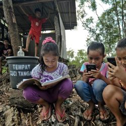Estudiantes de escuela primaria que estudian en línea usando sus teléfonos inteligentes para obtener una mejor conexión a Internet que en su aldea en la colina Temulawak, en Yogyakarta, el 8 de mayo de 2020. (Foto de AGUNG SUPRIYANTO / AFP) | Foto:AFP