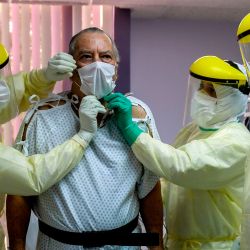 Herman Bern (L) de Panamá, un caso confirmado de COVID-19, es asistido por médicos en la unidad de cuidados intensivos del Hospital de Paitilla, después de que su última prueba de COVID-19 resultó negativa, en la ciudad de Panamá, el 6 de mayo de 2020. Bern pasó 50 días en la unidad de cuidados intensivos debido a COVID-19.Panamá acumuló 218 personas fallecidas y casi 8,000 infecciones por COVID-19. Alrededor de mil de los infectados se encuentran aislados en su hogar o en hoteles, 270 están hospitalizados en el suelo y 88 en la unidad de cuidados intensivos. (Foto por Luis ACOSTA / AFP) | Foto:AFP