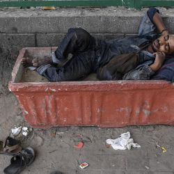 Un hombre sin hogar duerme dentro de una maceta en una carretera en Nueva Delhi el 10 de mayo de 2020. (Foto de SAJJAD HUSSAIN / AFP) | Foto:AFP