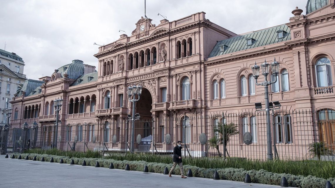 A pedestrian wearing a protective mask walks in front of the Casa Rosada in Buenos Aires.