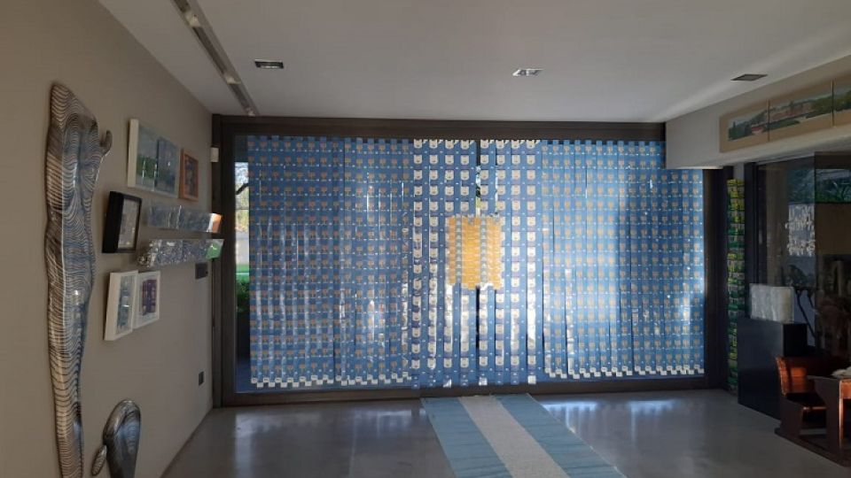 AL GRAN PUEBLO ARGENTINO SALUD. Sara Goldman tapó un ventanal con tiras de papel y cartón e intervino una bandera argentina con los acontecimientos provocados por el COVID-19.