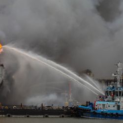 Los bomberos a bordo de una embarcación intentan extinguir un incendio en un buque cisterna atracado en Belawan el 11 de mayo de 2020. (Foto de Ivan Damanik / AFP) | Foto:AFP