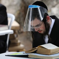 Los judíos ultraortodoxos que usan equipo de protección y observan el distanciamiento social en medio de la pandemia COVID-19, estudian el Talmud y la literatura rabínica en un Kollel improvisado al aire libre (lugar de reunión para estudios religiosos) en un parque en su vecindario ultraortodoxo en Jerusalén, en mayo. 11, 2020. (Foto de MENAHEM KAHANA / AFP) | Foto:AFP