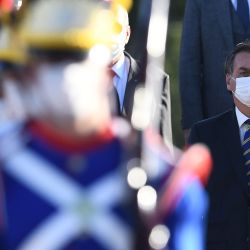 El presidente brasileño, Jair Bolsonaro, usa una máscara facial mientras asiste a la ceremonia de izado de la bandera antes de una reunión ministerial en el Palacio Alvorada en Brasilia, el 12 de mayo de 2020, en medio de la nueva pandemia de coronavirus. (Foto de EVARISTO SA / AFP) | Foto:AFP