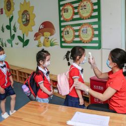 Esta foto tomada el 11 de mayo de 2020 muestra a un miembro del personal que controla la temperatura corporal de los niños antes de que ingresen a un aula en un jardín de infantes en Yongzhou, en la provincia central china de Hunan. - China no reportó nuevas infecciones domésticas por coronavirus el 12 de mayo, luego de dos días consecutivos de aumentos de dos dígitos alimentaron los temores de una segunda ola de infecciones. (Foto por STR / AFP) / China OUT | Foto:AFP