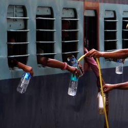 Un policía llena botellas con agua potable para los trabajadores migrantes de un servicio especial de trenes que parten hacia Uttar Pradesh después de que un gobierno alivió un bloqueo nacional como medida preventiva contra el coronavirus COVID-19, en Ajmer el 18 de mayo de 2020. (Foto de Himanshu SHARMA / AFP) | Foto:AFP