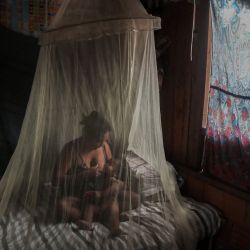 La madre indígena Satere-Mawe, Priscila Tavares Batista, de 36 años, amamanta a su hijo Jone Tavares, de 2 años, en una cama protegida por una mosquitera, después de ser tratada con hierbas medicinales después de mostrar síntomas de COVID-19, en la comunidad de Wakiru, en el barrio de Taruma. una zona rural al oeste de Manaus, estado de Amazonas, Brasil, el 17 de mayo de 2020, durante la nueva pandemia de coronavirus. - Según el líder indígena de Satere-Mawe, Andre Satere, once personas en su comunidad muestran síntomas de COVID-19. Los gobiernos locales y estatales fueron llamados a ayudar en vano. Con el sistema de salud del estado de Amazonas saturado, los indígenas recurren a sus conocimientos ancestrales sobre la naturaleza de la región para mantenerse saludables y tratar los posibles síntomas del nuevo coronavirus. (Foto por Ricardo OLIVEIRA / AFP) | Foto:AFP