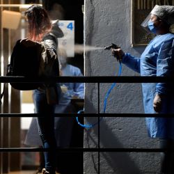 Una mujer desinfecta a un empleado como medida preventiva contra la propagación del nuevo coronavirus COVID-19, antes de comenzar su turno en una fábrica de artículos de cuero en Bogotá, el 19 de mayo de 2020. (Foto de Raul ARBOLEDA / AFP) | Foto:AFP