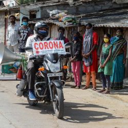 El agricultor Bamandla Ravinder, que recorre su bicicleta en las aldeas del estado de Telangana para dar a conocer el coronavirus COVID-19, viaja mientras la gente lo observa en los barrios bajos de Hyderabad el 21 de mayo de 2020. (Foto de NOAH SEELAM / AFP) | Foto:AFP