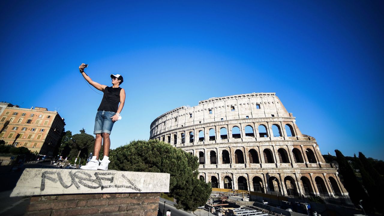 Un joven toma una foto selfie junto al monumento del Coliseo en Roma el 21 de mayo de 2020, mientras el país alivia su bloqueo después de más de dos meses, con el objetivo de frenar la propagación de la infección por COVID-19, causada por el nuevo coronavirus. (Foto por Filippo MONTEFORTE / AFP) | Foto:AFP