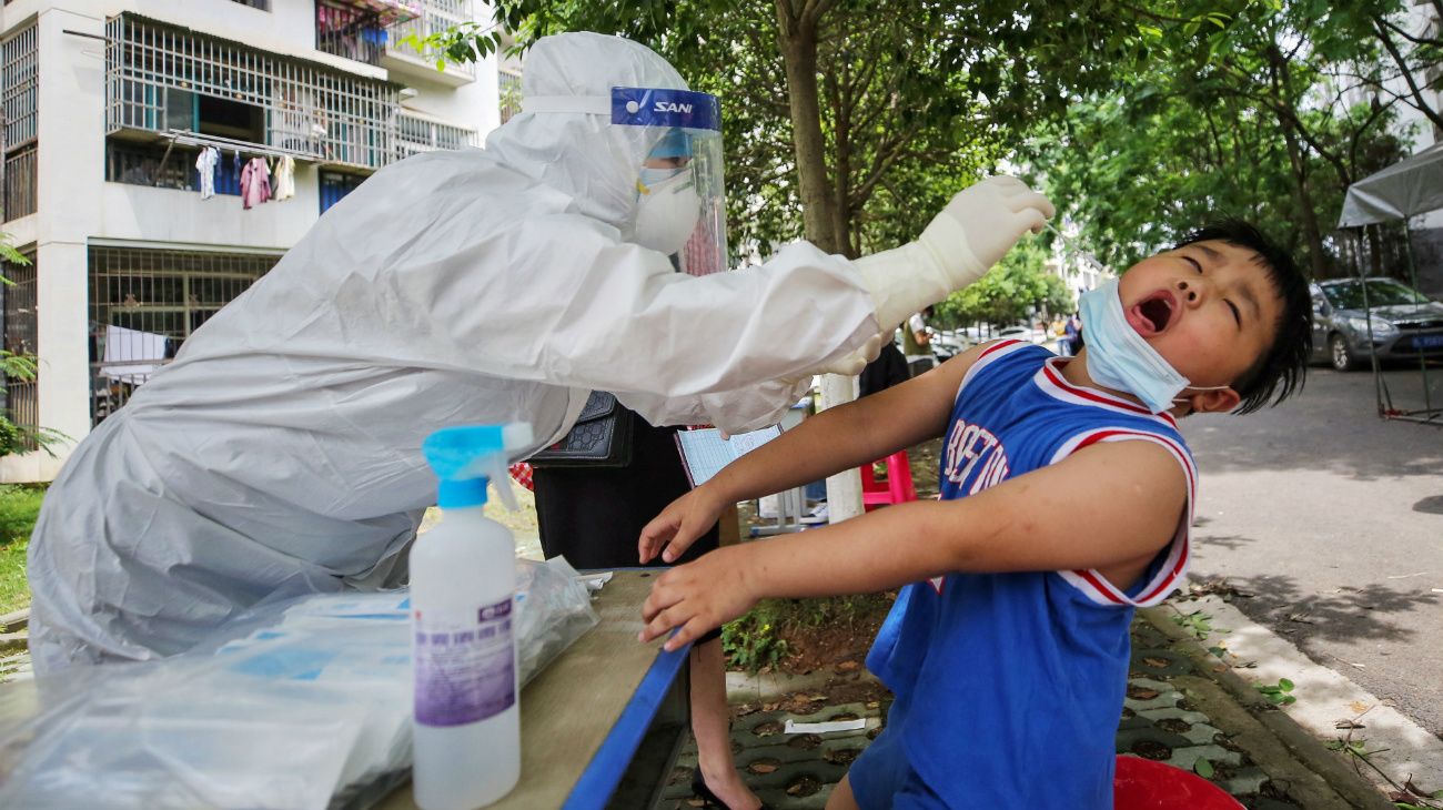 Un trabajador médico toma una muestra de un niño para analizar el coronavirus en una calle de Wuhan, China