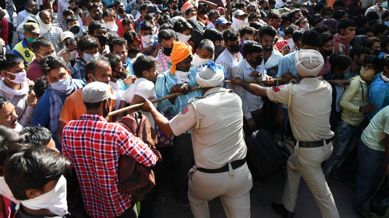 India: Policías frente a trabajadores migrantes varados mientras se reúnen para un examen médico antes de tomar un tren a Sultanpur para regresar a sus ciudades de origen