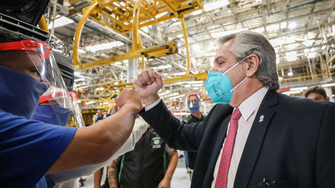 Handout picture released by Presidency shows President Alberto Fernández (right) greeting a worker at a Volkswagen Argentina factory after it restarted production, in General Pacheco, Buenos Aires Province, on May 19, 2020.