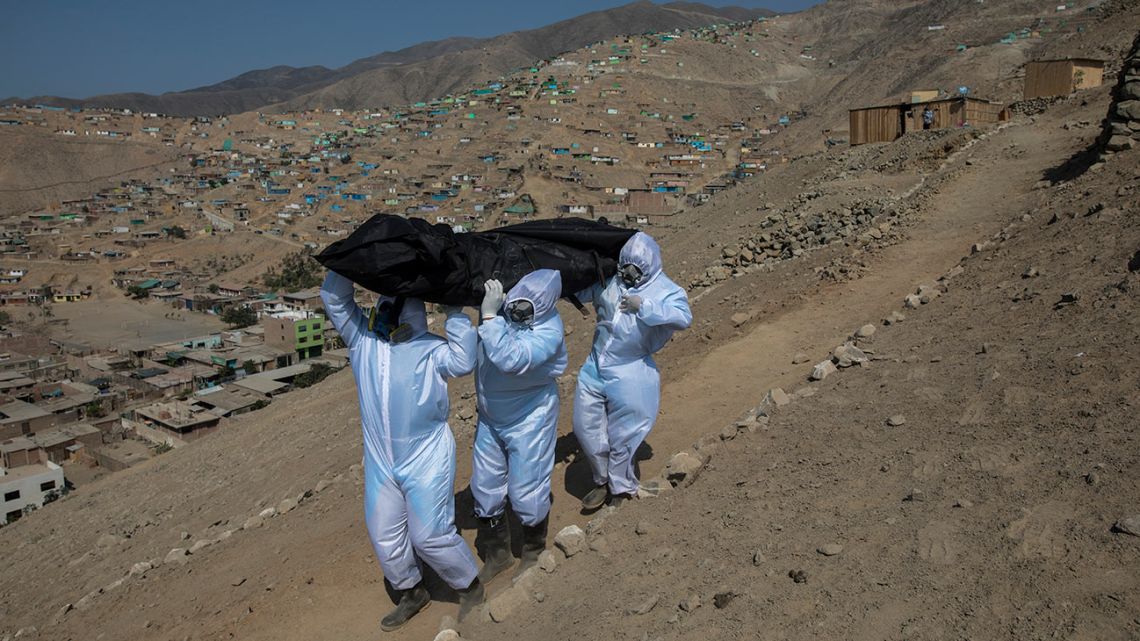 Venezuelans Luis Zerpa, from left, Luis Brito and Jhoan Faneite, carry a body bag that contains the remains of 51-year-old Marcos Espinoza who is suspected to have died of the new coronavirus, down a steep hill to a waiting hearse in a working-class neighbourhood near Pachacamac, the site of an Inca temple, on the outskirts of Lima, Peru, Friday, May 8, 2020.