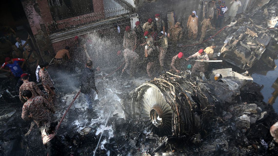 Volunteers look for survivors of a plane that crashed in residential area of Karachi, Pakistan, May 22, 2020. An aviation official says a passenger plane belonging to state-run Pakistan International Airlines carrying more than 100 passengers and crew has crashed near the southern port city of Karachi.