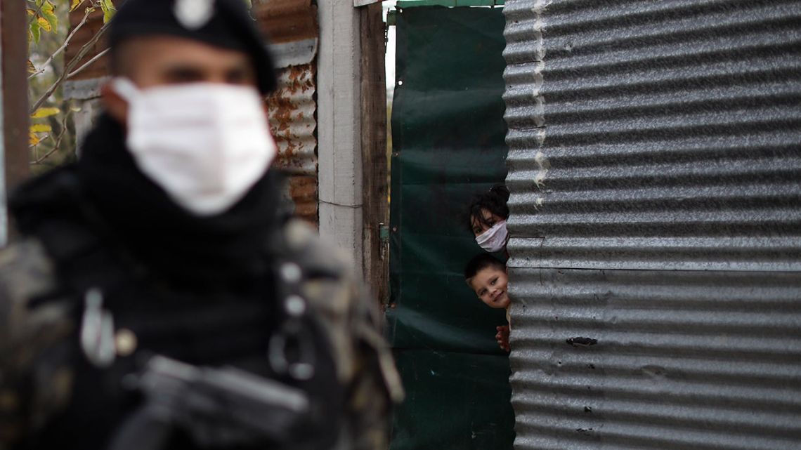 Children peer from their home as police guard the Villa Azul neighbourhood while it is isolated by authorities for quarantine after at least 50 people tested positive for the new coronavirus, according to government health officials, on the outskirts of Buenos Aires.