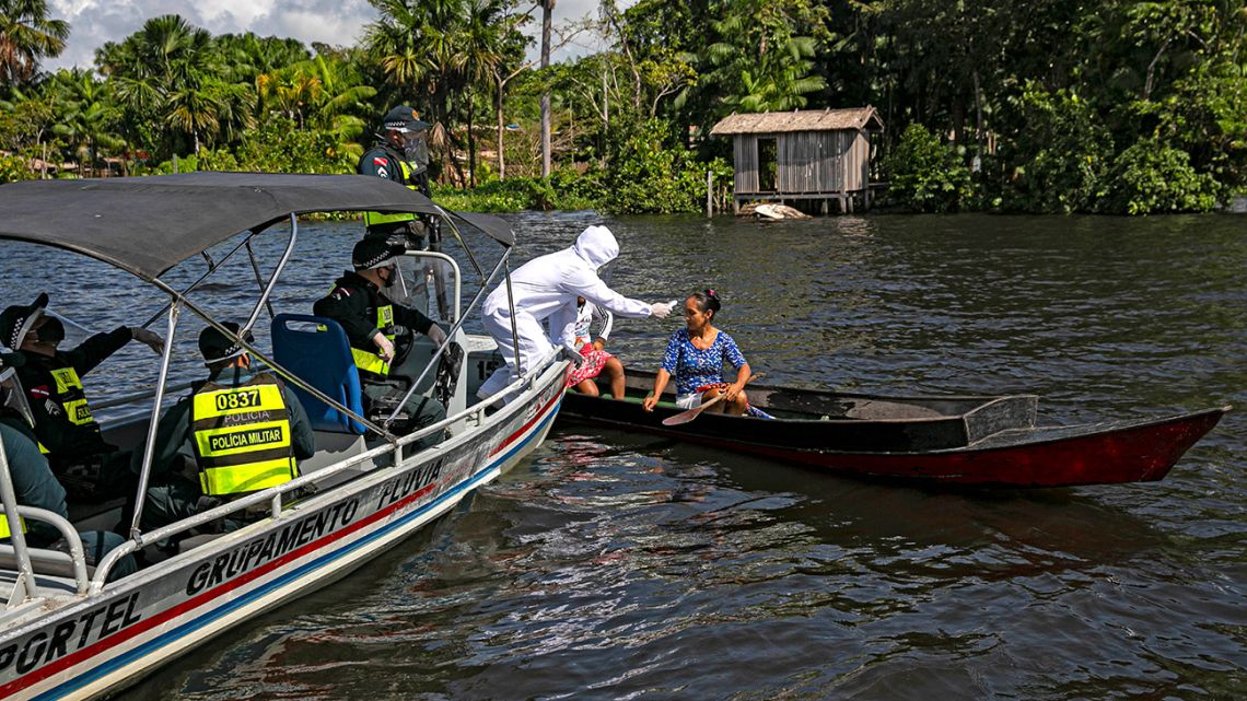 A government medical worker, in a joint operation with military police, checks a passenger on a boat in the Melgaco bay, southwest of the island of Marajo, Para state, Brazil, on May 27, 2020. People onboard small boats, ferries and ships on the river had their body temperature checked as authorities try to combat the new coronavirus. 