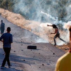 Un manifestante palestino devuelve un bote de gas lacrimógeno durante enfrentamientos con soldados israelíes en la ciudad de Tuqua en Cisjordania ocupada por Israel el 28 de mayo de 2020. (Foto de Musa Al SHAER / AFP) | Foto:AFP