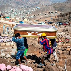 Los familiares llevan el ataúd de una presunta víctima de COVID-19 en el cementerio de Nueva Esperanza, uno de los más grandes de América Latina, en las afueras del sur de Lima. | Foto:Ernesto Benavides / AFP)
