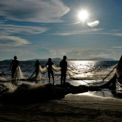 Indonesia. Los pescadores limpian una red después de pescar en una playa de Banda Aceh. | Foto:CHAIDEER MAHYUDDIN / AFP
