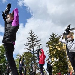 Los jóvenes atletas de la escuela de gimnasia rítmica, encabezados por Irina Deryugina, entrenadora principal del equipo ucraniano de gimnasia rítmica, usan máscaras protectoras y guantes, en medio de la pandemia continua de coronavirus COVID-19, mientras actúan durante la sesión de entrenamiento al aire libre. | Foto:Sergei Supinsky / AFP