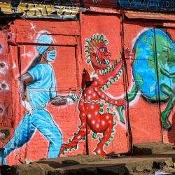 Una mujer pasa junto al mural de graffiti relacionado con el coronavirus COVID-19 pintado por el grupo de arte residencial, art360, en el barrio marginal de Kibera en Nairobi. | Foto:Gordwin Odhiambo / AFP