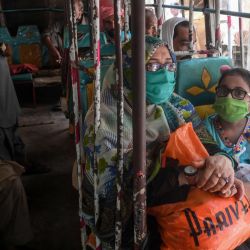 La gente se sienta en un mini bus después de que el gobierno reanudó los servicios de transporte público aliviando el bloqueo impuesto contra el coronavirus COVID-19, en la ciudad portuaria de Karachi en Pakistán. | Foto:Asif Hassan / AFP