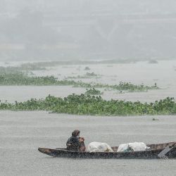 La gente se dirige en un bote durante una lluvia en el río Buriganga en Dhaka, Bangladesh. | Foto:MUNIR UZ ZAMAN / AFP