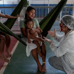Un miembro de Médicos sin Fronteras mira a un niño de la tribu Warao, el segundo grupo indígena más grande de Venezuela, que sufre los síntomas del nuevo coronavirus en Manaos, estado de Amazonas, Brasil. | Foto:MICHAEL DANTAS / AFP 