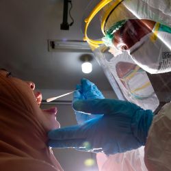 Indonesia. Un miembro del personal médico que usa equipo de protección personal recolecta una muestra de hisopo para evaluar el coronavirus COVID-19 de un empleado del gobierno en una oficina municipal en Banda Aceh. | Foto:CHAIDEER MAHYUDDIN / AFP