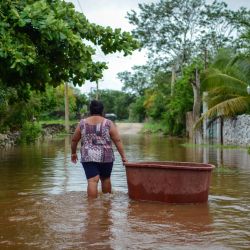 Una mujer de la comunidad maya de Tecoh vadea por el agua en una inundación causada por la tormenta tropical Cristóbal en la ciudad de Tecoh, cerca de Mérida, en el estado de Yucatán, México. | Foto:Luis Perez / AFP
