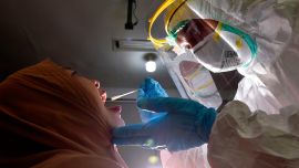Indonesia. Un miembro del personal médico que usa equipo de protección personal recolecta una muestra de hisopo para evaluar el coronavirus COVID-19 de un empleado del gobierno en una oficina municipal en Banda Aceh.