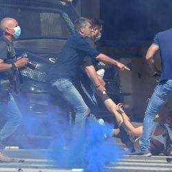 Policías vestidos de civil detienen a un manifestante (abajo) durante los enfrentamientos entre la policía antidisturbios y los grupos neofascistas, extremistas y ultras de los clubes de fútbol de Italia que se manifiestan por el manejo del gobierno de la emergencia del coronavirus. | Foto:Andreas Solaro / AFP