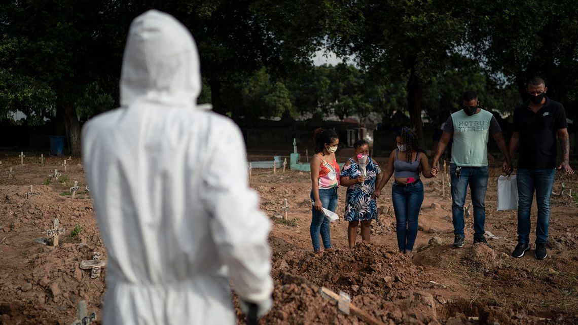Relatives attend the burial of 57-year-old Paulo Jose da Silva, who died from the new coronavirus, in Rio de Janeiro, Brazil, Friday, June 5, 2020. According to Monique dos Santos, her stepfather mocked the existence of the virus, didn't use a mask, didn't take care of himself, and wanted to shake hands with everybody. "He didn't believe in it and unfortunately he met this end. It's very sad, but that's the truth," she said.