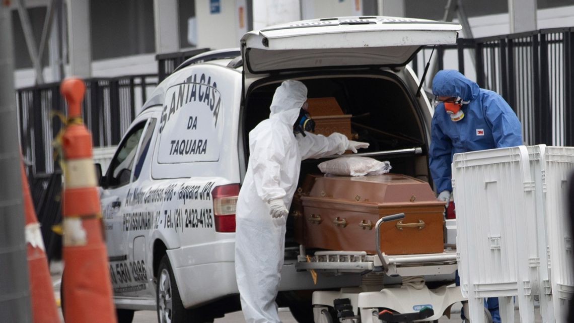 Funeral workers wearing protective gear as a precaution amid the new coronavirus pandemic push the remains of a Covid-19 victim into a funeral car at a field hospital in Leblon, Rio de Janeiro, Brazil, Thursday, June 4, 2020. 