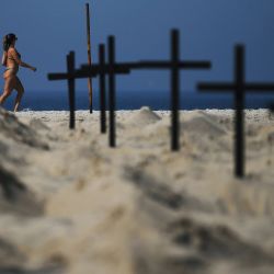 Los visitantes de la playa caminan frente a 100 tumbas simuladas excavadas por activistas de la ONG brasileña Río de Paz (Peace Rio), que simboliza las muertes por el coronavirus COVID-19 en Río de Janeiro, Brasil. | Foto:CARL DE SOUZA / AFP