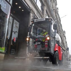 Un trabajador rocía una solución de limpieza en un pavimento fuera de las tiendas en Regent Street en el centro de Londres. | Foto:JUSTIN TALLIS / AFP